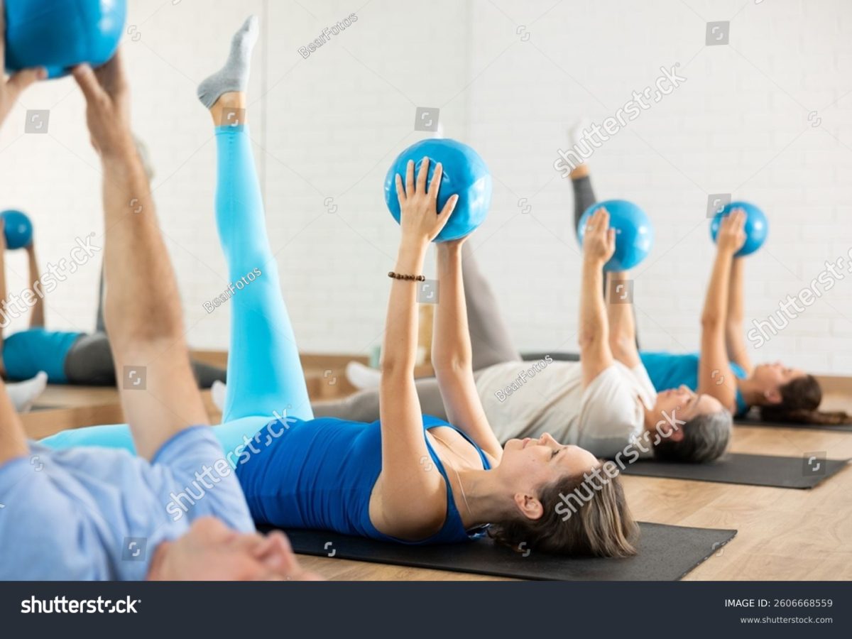 stock-photo-group-of-young-mature-old-people-in-sportswear-exercising-pilates-with-balls-in-hands-while-lying-2606668559